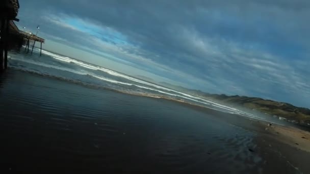 새벽에 해안선에 부두의 버팀대 사이를 드론을 비행하는 — 비디오