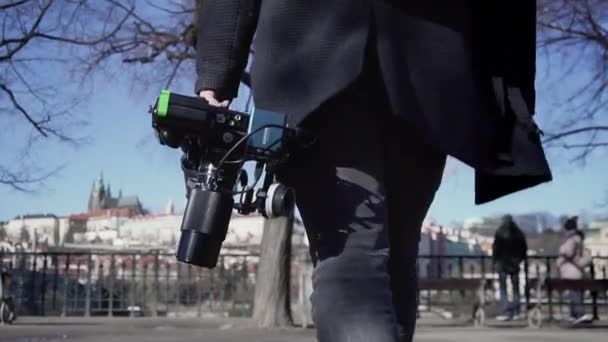 三脚とカメラギアを持っているオペレーター 場所に歩いて バックグラウンドでプラハで撮影したクローズアップ移動 — ストック動画