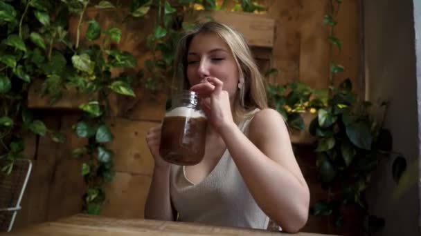 Šťastná mladá blondýnka žena pití koktejl sklenice sedí u kavárny