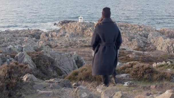 Жінка Дивиться Маяк Заході Сонця Скелястій Скелі Поки Пальто Хвилі — стокове відео