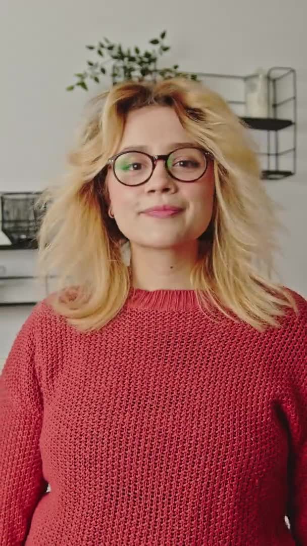 Pionowe Wideo Blondynka Okularach Falowanymi Włosami Odwraca Głowę Patrząc Kamerę — Wideo stockowe