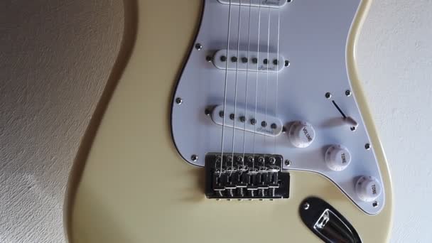 Grädde Vit Elektrisk Stratocaster Gitarr Hängande Framför Vit Vägg Handhållen — Stockvideo