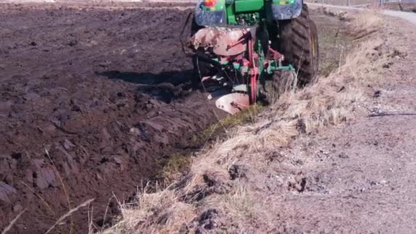 Green Farm Tractor Plows Dry Land Field Sunny Spring Day — Stock Video