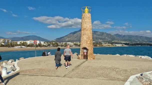 4Kスペインのマルベージャの有名なプエルト バヌス湾を歩く人々のショット マルベージャの豪華かつ有名な目的地 コンチャ山を背景に — ストック動画