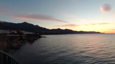 Pan across stunning silhouette sunset at ocean with mountains in background