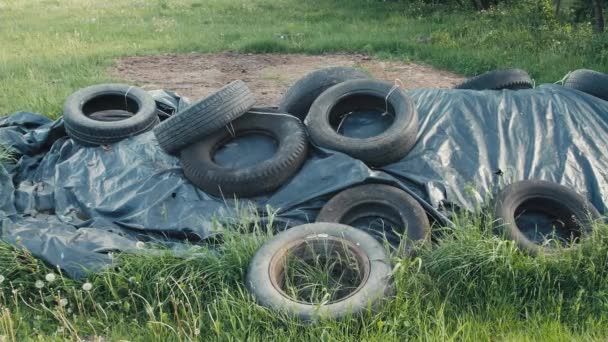 Old Worn Tires Lie Black Foil Covers Compost Green Grass — Vídeo de Stock