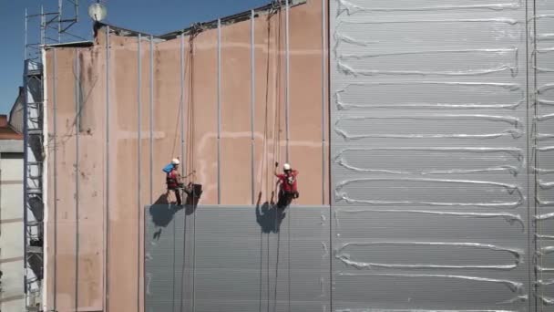 Deux Ouvriers Construction Suspendus Dans Une Façade Tout Réparant Vieux — Video
