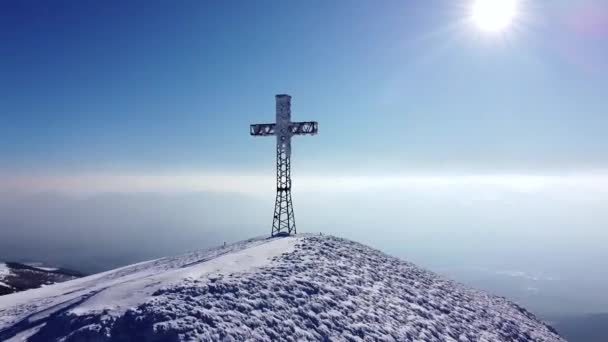 風光明媚な山の紋章の上に十字架と空中の高山のピークは 無人機は リモート汚染されていない自然環境の中で素晴らしい自然の冬の雪の覆われた風景を明らかに — ストック動画