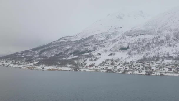 ノルウェーのオルダーデンにある山の麓にあるKfjord町と港 冬の天候をオーバーキャストします フィヨルドに向かって横回転運動と4K空中ドローンショット — ストック動画
