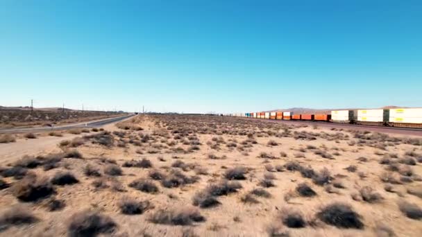 Drone Volando Bajo Siguiendo Tren Carga Cruzando Desierto Cielo Azul — Vídeos de Stock