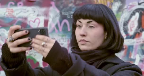 Interesante Mujer Haciendo Selfie Teléfono Móvil Frente Lennon Wall Llena — Vídeo de stock