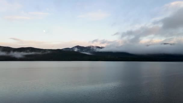 ニュージーランドの日没時に美しい反射湖の空中ドローンショット 水の上を飛んで 雲の背景に低いぶら下げ — ストック動画