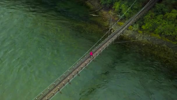 Πεζοπόρος Περπατώντας Μια Ξύλινη Κρεμαστή Γέφυρα Διασχίζοντας Ένα Μεγάλο Ποτάμι — Αρχείο Βίντεο
