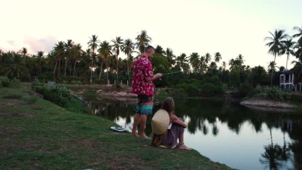 在越南热带湖畔钓鱼的年轻夫妇 静观后景 — 图库视频影像