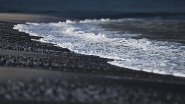 海浪缓缓地在沙滩上滚着 背景中一个人和一只狗模糊的轮廓 慢动作 — 图库视频影像