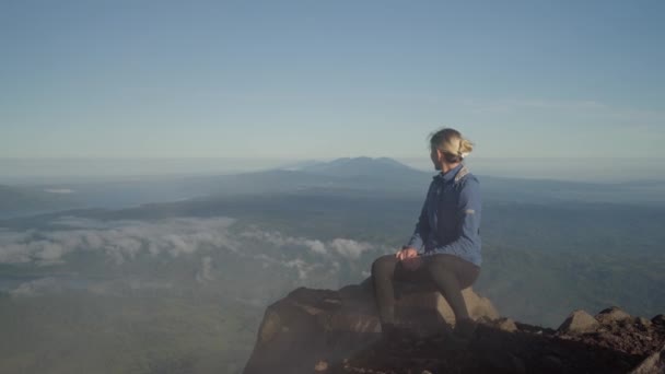 Блондинка Туристка Сидит Краю Скалы Смотрит Захватывающий Вид Вулканической Вершины — стоковое видео