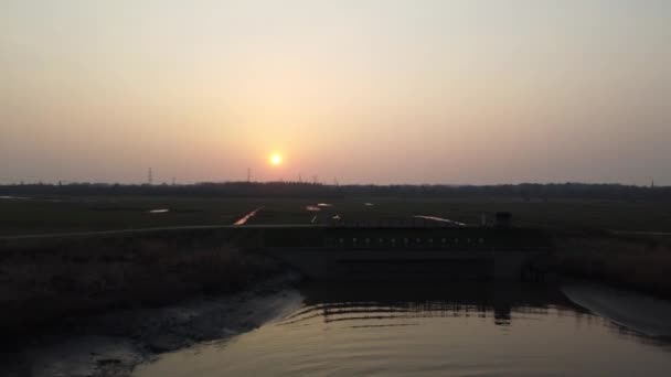 Slunce zapadá za siluetu zemědělských polí a kanálů v Belgii, letecký pohled