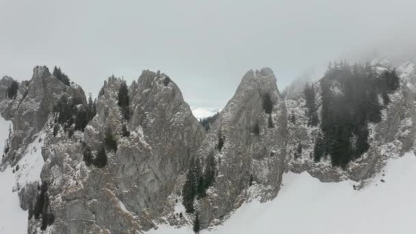 厚い霧の中で山の峰の間を飛行し 美しい雪に覆われた谷を明らかにドローン — ストック動画