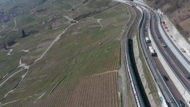忙しい高速道路の隣を走行しながら2本の列車がすれ違う空中 — ストック動画
