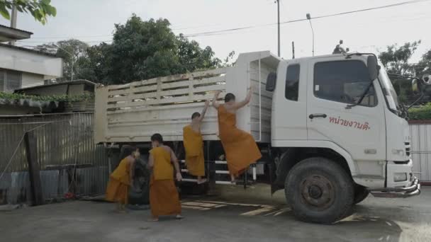 顔のマスクの面白い若い僧侶が田舎の駐車場でトラックに登る — ストック動画