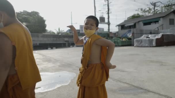 Funny lively young monk dancing in a square in Bangkok rural area 