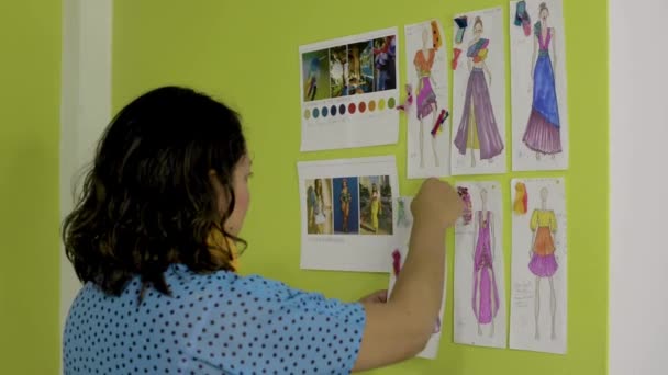 Diseñadora Moda Latina Trabajando Arreglando Varios Bocetos Pared Para Nueva — Vídeos de Stock