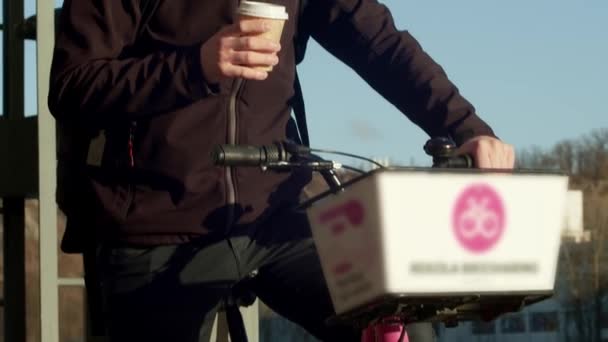 Ένας Νεαρός Κοινόχρηστο Ποδήλατο Απολαμβάνει Ένα Φλιτζάνι Καφέ Ένα Ηλιόλουστο — Αρχείο Βίντεο