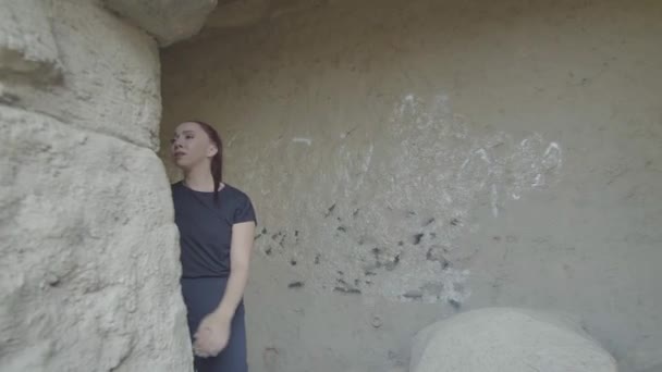 Strzał Śledzący Białą Kobietę Idącą Stronę Kamiennej Ściany Zerkającą Niej — Wideo stockowe