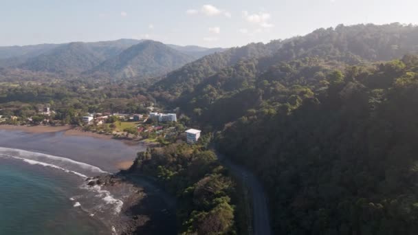 コスタリカ中部太平洋沿岸の緑豊かなジャングルの山々やビーチに囲まれた美しい海岸沿いの町 ジャコ ショットで広角の空中プッシュ — ストック動画