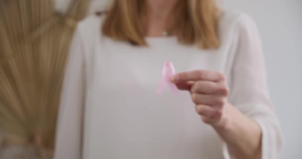 金发女人展示粉红十月的象征 肤浅的焦点 — 图库视频影像