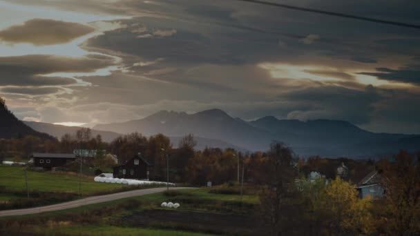 在北方的小村庄上空 夕阳西下 乌云密布 后面是多雾的山 远距离射击 慢动作 — 图库视频影像