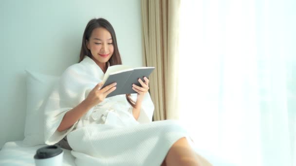 Genç Bir Kadın Kitap Okurken Parlak Bir Pencerenin Yanındaki Yatakta — Stok video