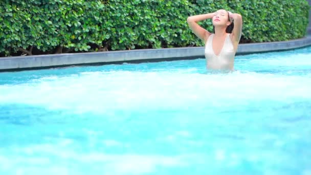 身穿泳衣的妇女紧闭双眼 在游泳池里向旋转的温泉泡泡走去 在热带旅游胜地享用豪华温泉度假设施的亚洲女士 — 图库视频影像