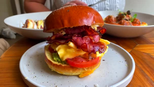 美味的早餐汉堡包 西红柿 切达芝士 鳄梨和牛肉饼 早午餐餐厅 在后台吃饭 4K杯 — 图库视频影像