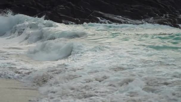 Close Shot Long Waves Spilling Sandy Shore Jagged Rocks Background — ストック動画