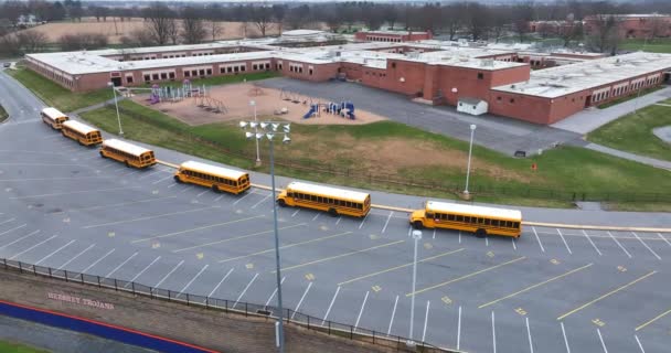 アメリカの学校で黄色のスクールバスラインは 学生を待っている 建物や遊び場のリセックス機器 空中設置ショット — ストック動画