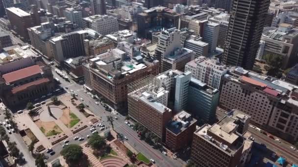 Aerial forward tracking aerial of downtown Johannesburg city center streets, tall buildings, office blocks with cars and pedestrians. Morning time.