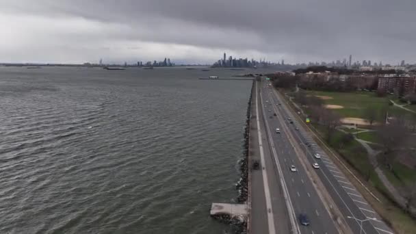 位于纽约布鲁克林的上海湾 俯瞰着沿着环带大道的铺面人行道的空中景观 在一个寒冷多云的夜晚 无人驾驶相机向纽约市的天际线飞去 — 图库视频影像