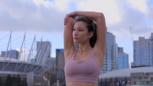 加拿大温哥华 一个女人在体育场和建筑物旁做三头肌伸展运动 — 图库视频影像