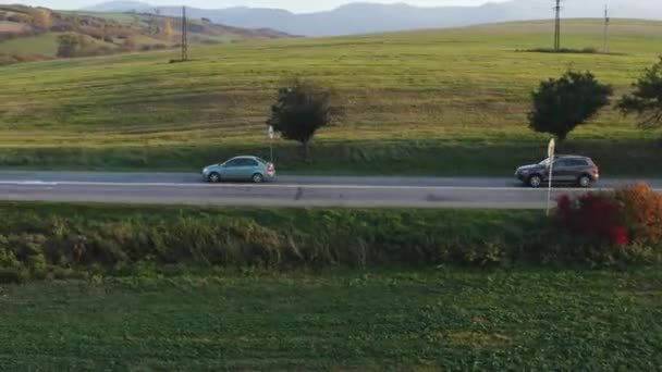 2台の車は スロバキア ヨーロッパの広大な オープン風景を介して農村部 国の道路に沿って旅行 空中フォローショット側 — ストック動画