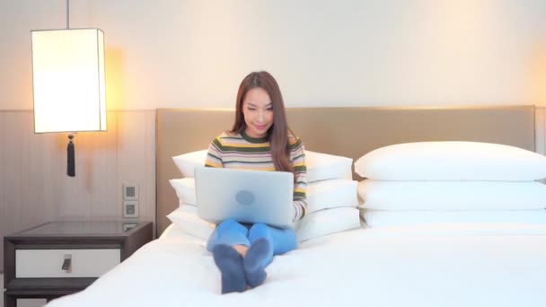 ベッドに座っている若い女性がノートパソコンで働いていると笑顔になる タイトル空間 — ストック動画