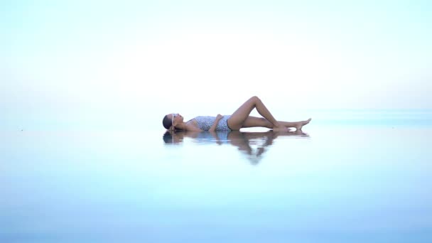 一个女人躺在一个无限大的池子的浅端 给人一种飘浮在半空中的错觉 标题空间 — 图库视频影像