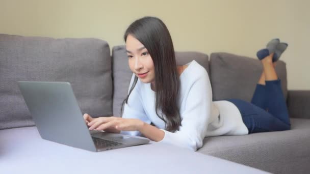 Kanepede Yüzüstü Yatan Genç Bir Kadın Laptopunda Başarıyla Çalışıyor — Stok video