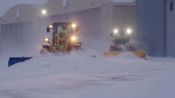 暴风雪期间 两台雪犁拖拉机在机场道路上清除厚厚的积雪 — 图库视频影像