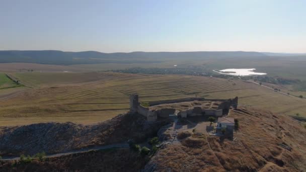 在阳光明媚的日子里 在一座被湖泊和平原环绕的山丘顶上的中世纪要塞埃尼萨拉的无人驾驶飞机的长距离跟踪拍摄 — 图库视频影像