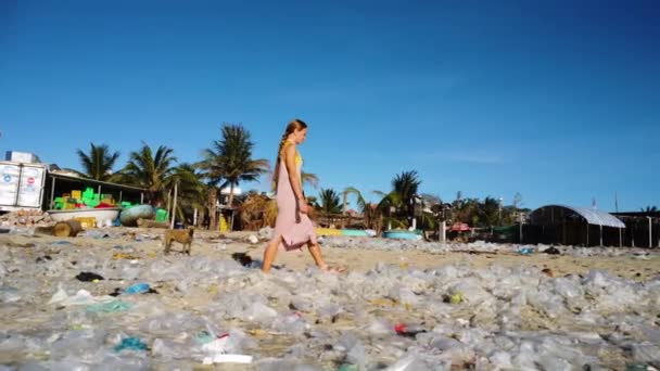 Caucasian woman walking in sandals on polluted beach with plastic bag waste, toxic garbage, ocean pollution concept, global warming
