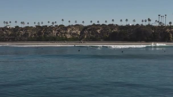 Krásný výstřel z bezpilotního letounu, letící nízko nad vodou podél pobřeží a natáčející pár surfařů, Karlovarská státní pláž - Kalifornie