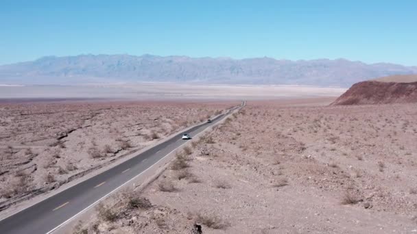 รถส ขาวข บบนถนนยางมะตอยผ านทรายทะเลทราย ภาพท เขาในพ นหล — วีดีโอสต็อก