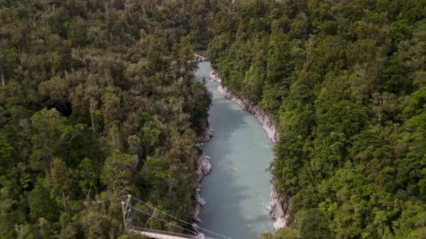 緑豊かな原生林に囲まれた北チカ渓谷のターコイズブルーと緑の水 吊り橋とニュージーランドの風景の空中公開 — ストック動画