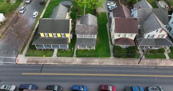 小さなアメリカの町の静かな通りに沿って古い家 昔ながらの2階建ての家族の家に黄色のサイド 早春の空中 — ストック動画